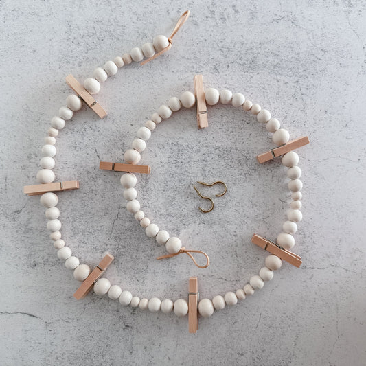 Decorative wreath made of white beads and wooden clips 