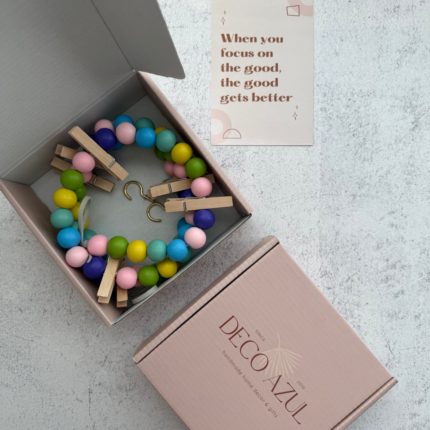 Rainbow garland with wooden clips in a box, branded 'Deco Azul'.
